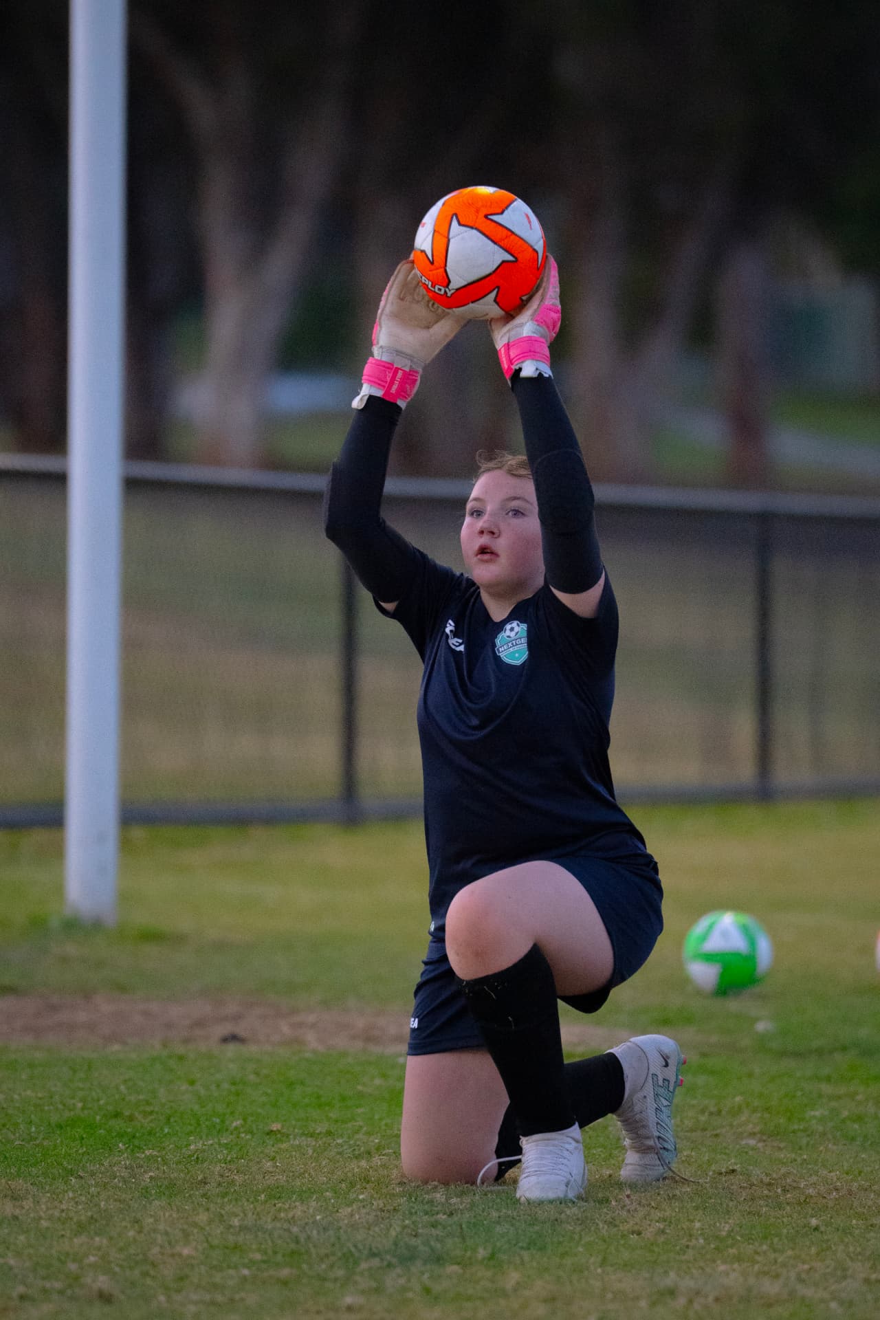 NextGen goalkeeper catching the ball overhead in front of the goal